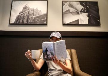 person reading a book and holding a cup of coffee