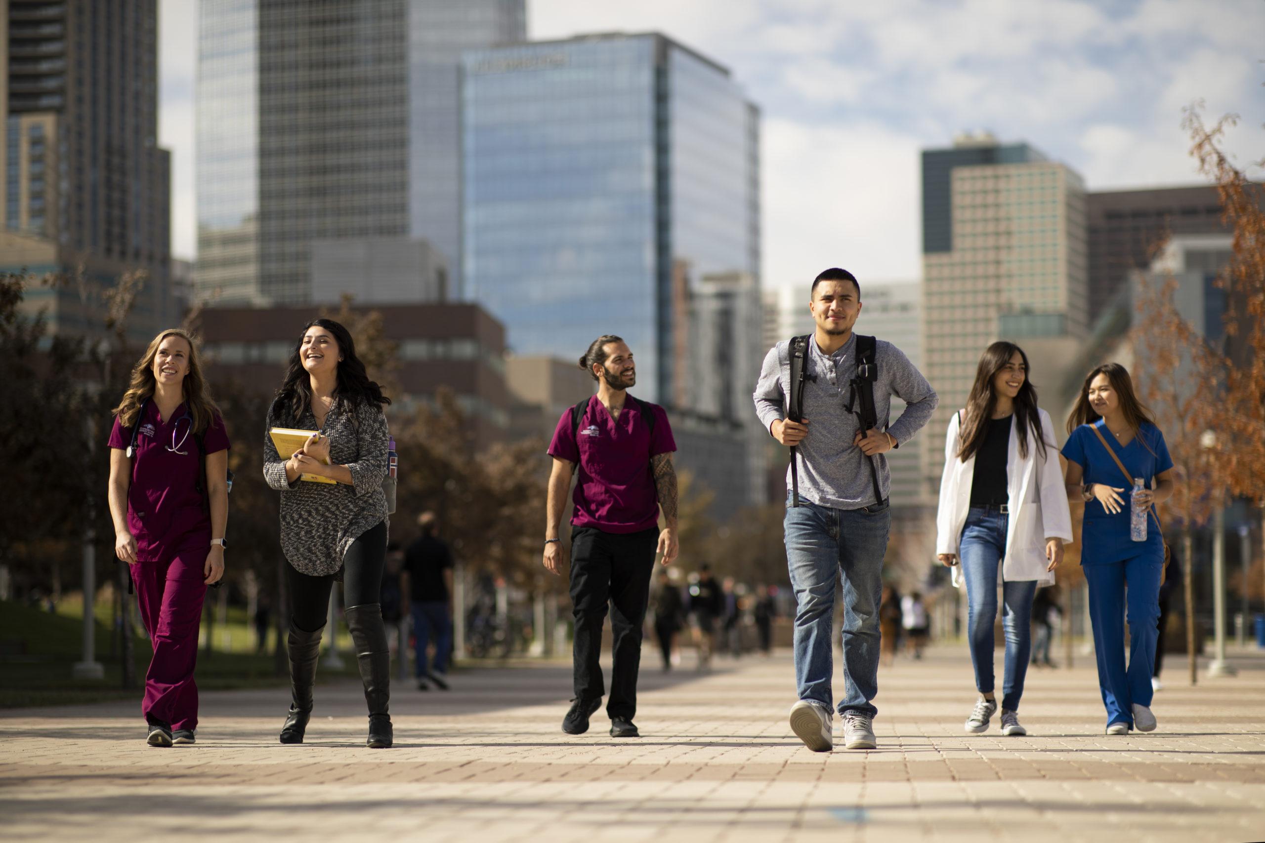 一群学生穿过校园，背景是丹佛市中心.