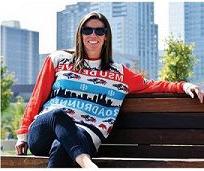Woman sitting on a bench on campus wearing a Roadrunners sweater with downtown in the background