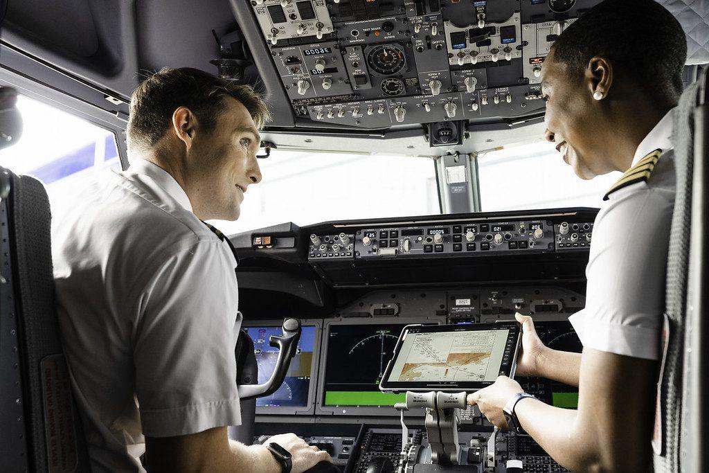 Two pilots having a discussion in the flight deck of a commercial aircraft.