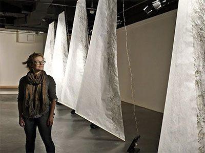 Professor Anne Yoncha in the gallery with large fabric sails behind.